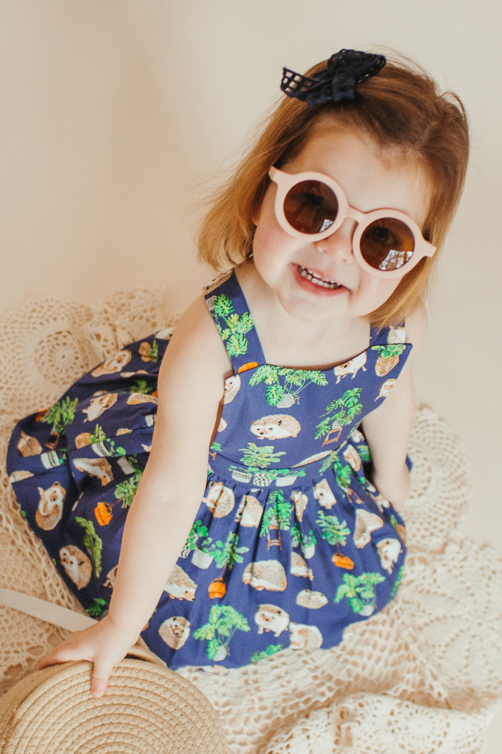 toddler in pinafore dress and sunnies